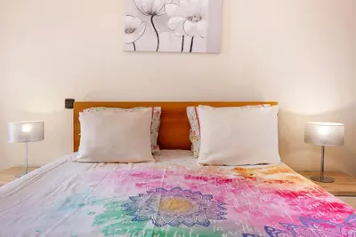 a bed with a colorful blanket on it with two lamps at Sunparadise in Arco da Calheta