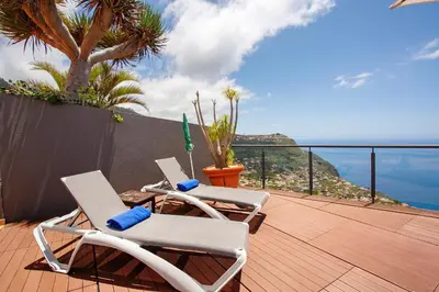 two chairs on a deck with a view of the ocean at Sunparadise in Arco da Calheta
