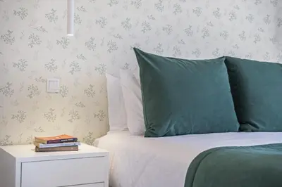 a bed with green pillows and a nightstand with a side table at Contemporary Residence C by Homie in Funchal