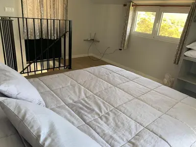 a bedroom with a large white bed with a window at Casa Jardim Panoramic View in Estreito da Calheta