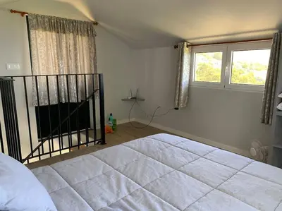 a bedroom with a large bed and two windows at Casa Jardim Panoramic View in Estreito da Calheta