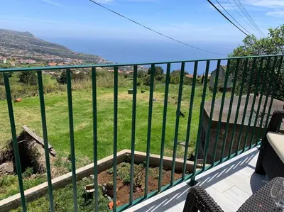 a balcony with a fence with a view of a field at Casa Jardim Panoramic View in Estreito da Calheta
