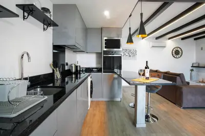 a kitchen with black and white cabinets and a table at Refugio Do Lourinho in Calheta