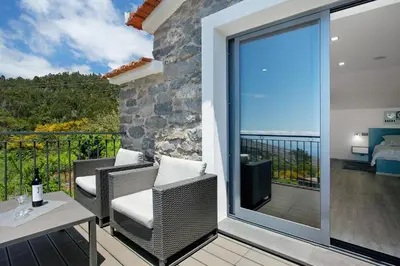 a balcony with wicker chairs and a sliding glass door with a view at Refugio Do Lourinho in Calheta