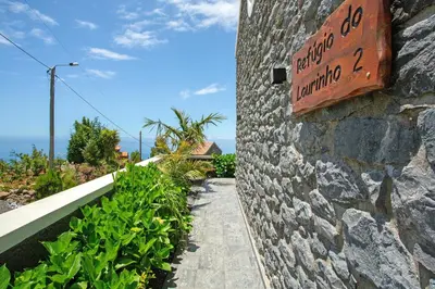 a stone wall with a sign on the side of a building at Refugio Do Lourinho in Calheta