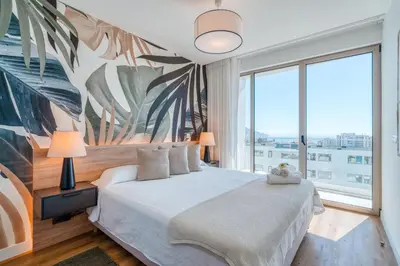 a bedroom with a large bed with a large window at The Pink Palm Apartment by Amazing Madeira in Funchal