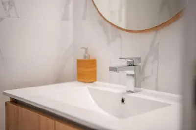 a white bathroom with a sink and a mirror at The Pink Palm Apartment by Amazing Madeira in Funchal