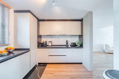 a kitchen with white cabinets and a wooden floor at The Pink Palm Apartment by Amazing Madeira in Funchal