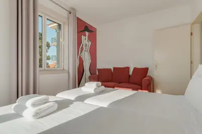 a bedroom with a white bed and a red chair at Old Town Apartment in Funchal