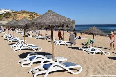 a row of lounge chairs and umbrellas on a beach at Apartamento Caravela em Burgau - NEW LISTING in Burgau