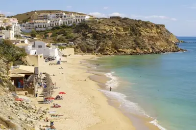 a beach with people laying on the sand and the water at Apartamento Caravela em Burgau - NEW LISTING in Burgau