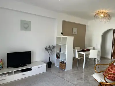 a living room with a television and a table with chairs at Apartamento Caravela em Burgau - NEW LISTING in Burgau