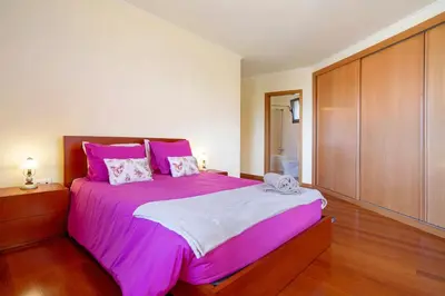 a bedroom with a pink bed with a wooden cabinet at Casa da Bemposta in Machico