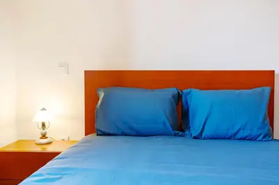 a blue bed with a wooden headboard and blue pillows at Casa da Bemposta in Machico