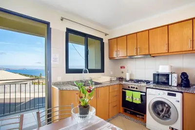 a kitchen with a washing machine and a table with a view at Casa da Bemposta in Machico