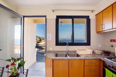 a kitchen with a washer and dryer and a balcony at Casa da Bemposta in Machico