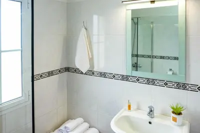 a white bathroom with a sink and a mirror at Casa do Simão Gaula in Santa Cruz