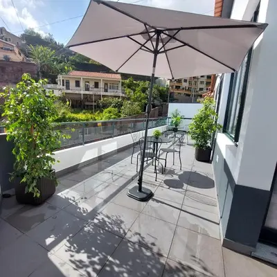 a patio with an umbrella and chairs on a balcony at Villa City in Funchal