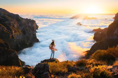 a woman standing on top of a mountain looking out over clouds at Apartment in Camara de Lobos not shared in Câmara de Lobos