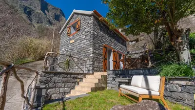 a stone house with a chair in front of it at Stonewood Valley by LovelyStay in Curral das Freiras