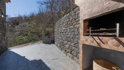 a building with a stone wall with a fireplace at Stonewood Valley by LovelyStay in Curral das Freiras