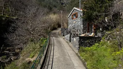 a train track in front of a stone building at Stonewood Valley by LovelyStay in Curral das Freiras