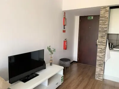 a living room with a flat screen tv on a white cabinet at Apartamento do Mar e Lua in Funchal