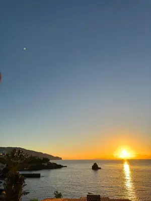 a sunset over a body of water with the sun setting at Apartamento do Mar e Lua in Funchal