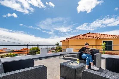 a woman sitting in a chair on a balcony with a laptop at City Haven by Homie in Funchal
