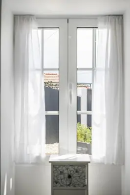 a window with white curtains and a table in front of it at City Haven by Homie in Funchal