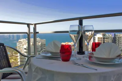 a table with wine glasses and plates on a balcony at Forum Apartment by HR Madeira in Funchal