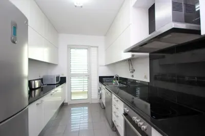 a kitchen with white cabinets and black counter tops at Forum Apartment by HR Madeira in Funchal