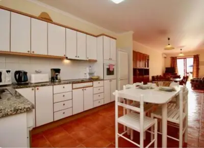 a kitchen with white cabinets and a white table and chairs at Angela Beach Place in Vila Baleira