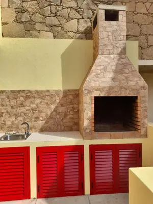 a kitchen with red cabinets and a stone fireplace at Angela Beach Place in Vila Baleira