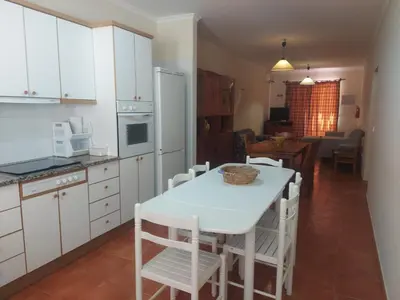 a kitchen with white cabinets and a table and chairs at Angela Beach Place in Vila Baleira