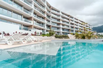a swimming pool with chairs and a building at GuestReady - The place to be happy in Madeira in Funchal