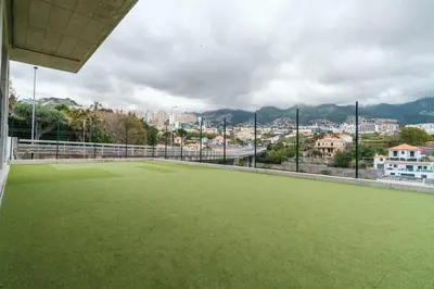 a large green field with a city in the background at GuestReady - The place to be happy in Madeira in Funchal