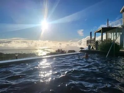 a person in a swimming pool with the sun in the sky at Horizon Retreat in Calheta