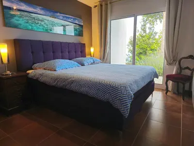 a bedroom with a bed with a purple headboard and a window at Horizon Retreat in Calheta