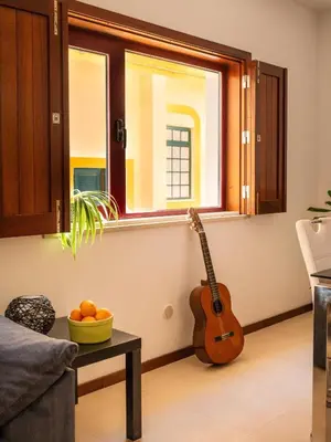 a guitar in the corner of a living room with a table at Casa Da Bélgica in Sagres