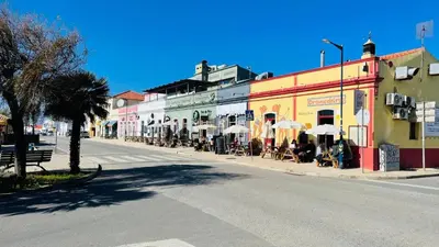 an empty street in a town with tables and umbrellas at Casa Da Bélgica in Sagres