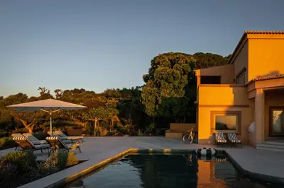 a white umbrella sitting on a hill next to the ocean at Casa Pôr do Sal in Luz