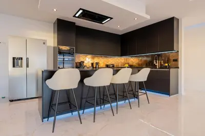 a kitchen with a bar with white stools at Villa Luxe by Atlantic Holiday in Ribeira Brava