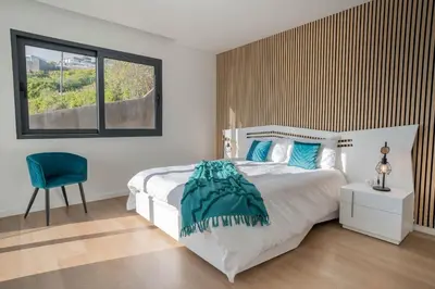 a bedroom with a bed and a chair and a window at Villa Luxe by Atlantic Holiday in Ribeira Brava