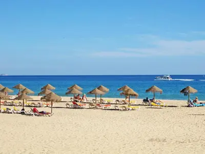 a group of people laying on a beach with umbrellas at Flat in Praia da Luz with Sea Views in Luz