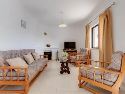 a living room with a couch and chairs and a tv at Casa Teresinha with private pool in Montinhos da Luz