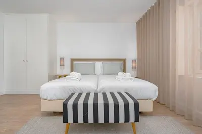 a white bedroom with a large bed and a black and white ottoman at Studios Funchal in Funchal