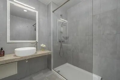 a bathroom with a shower and a sink and a mirror at Studios Funchal in Funchal