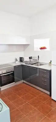a kitchen with stainless steel appliances and a brown tile floor at Apartamento renovado e luminoso a poucos minutos do centro in Funchal