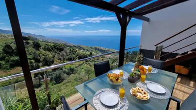 a table with food on a balcony with a view of the ocean at Valley Miradouro View by LovelyStay in Ponta do Sol